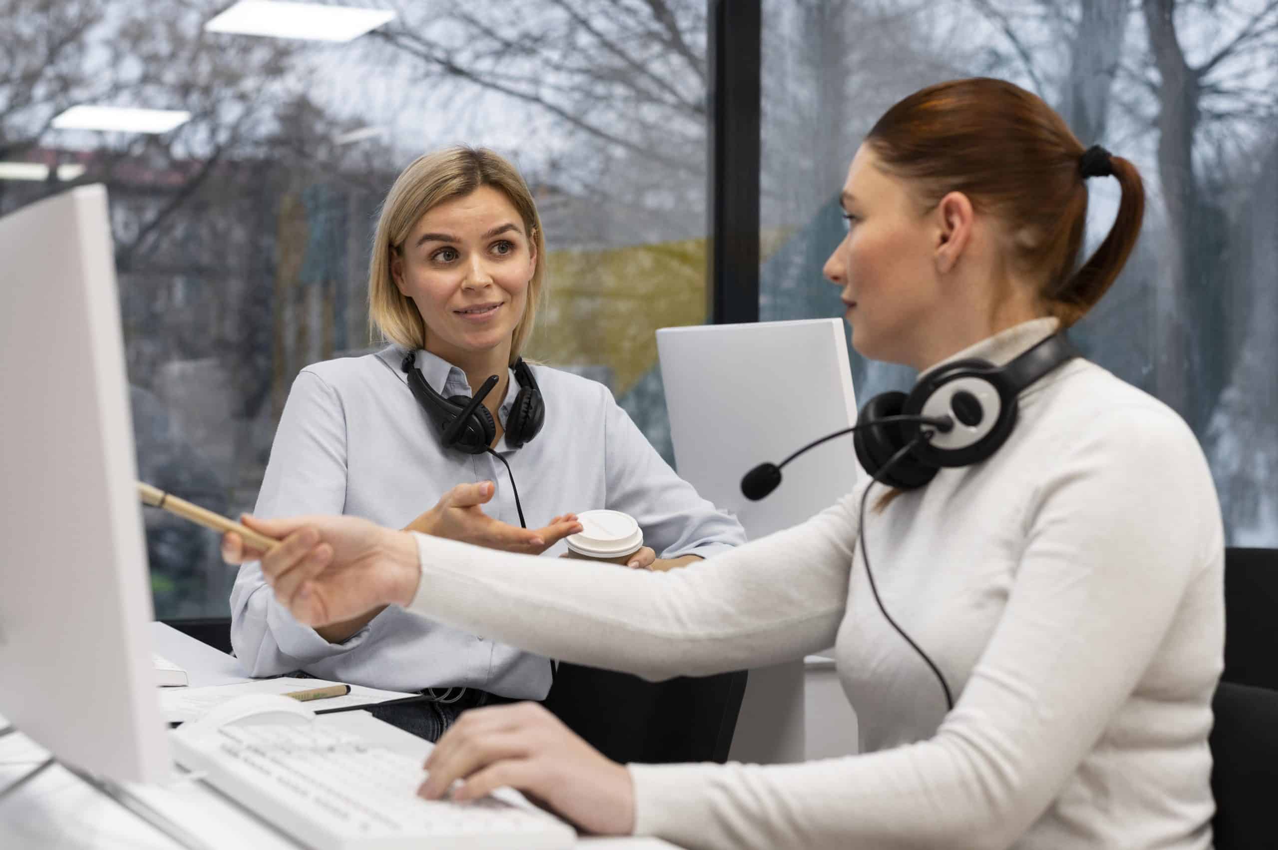 two-women-having-conversation-work-call-center-office-min