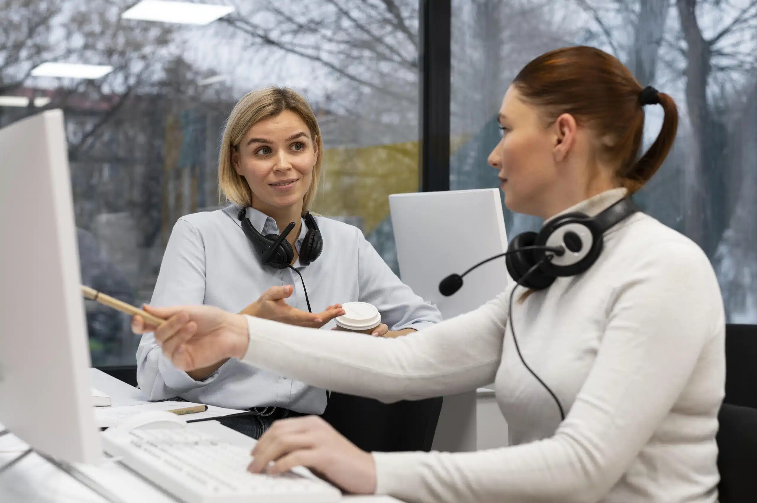 two-women-having-conversation-work-call-center-office-min